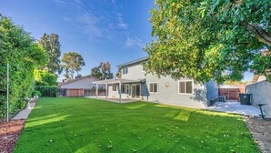A modern two-story house with a well-maintained lawn and a covered patio area. - @ Marbella Lane Modern Home w/ Private Backyard (Fullerton)