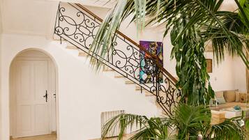 A staircase with ornate metal railings, a white door, and a living room area with a sofa and a coffee table.