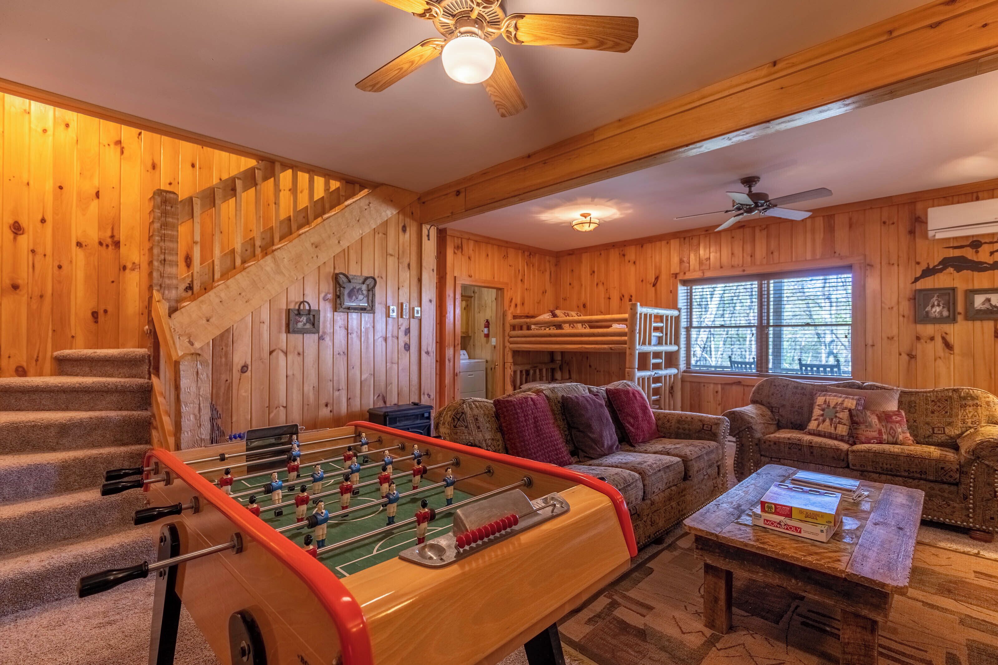 A cozy wooden-floored room with a foosball table, a sofa, and a coffee table.