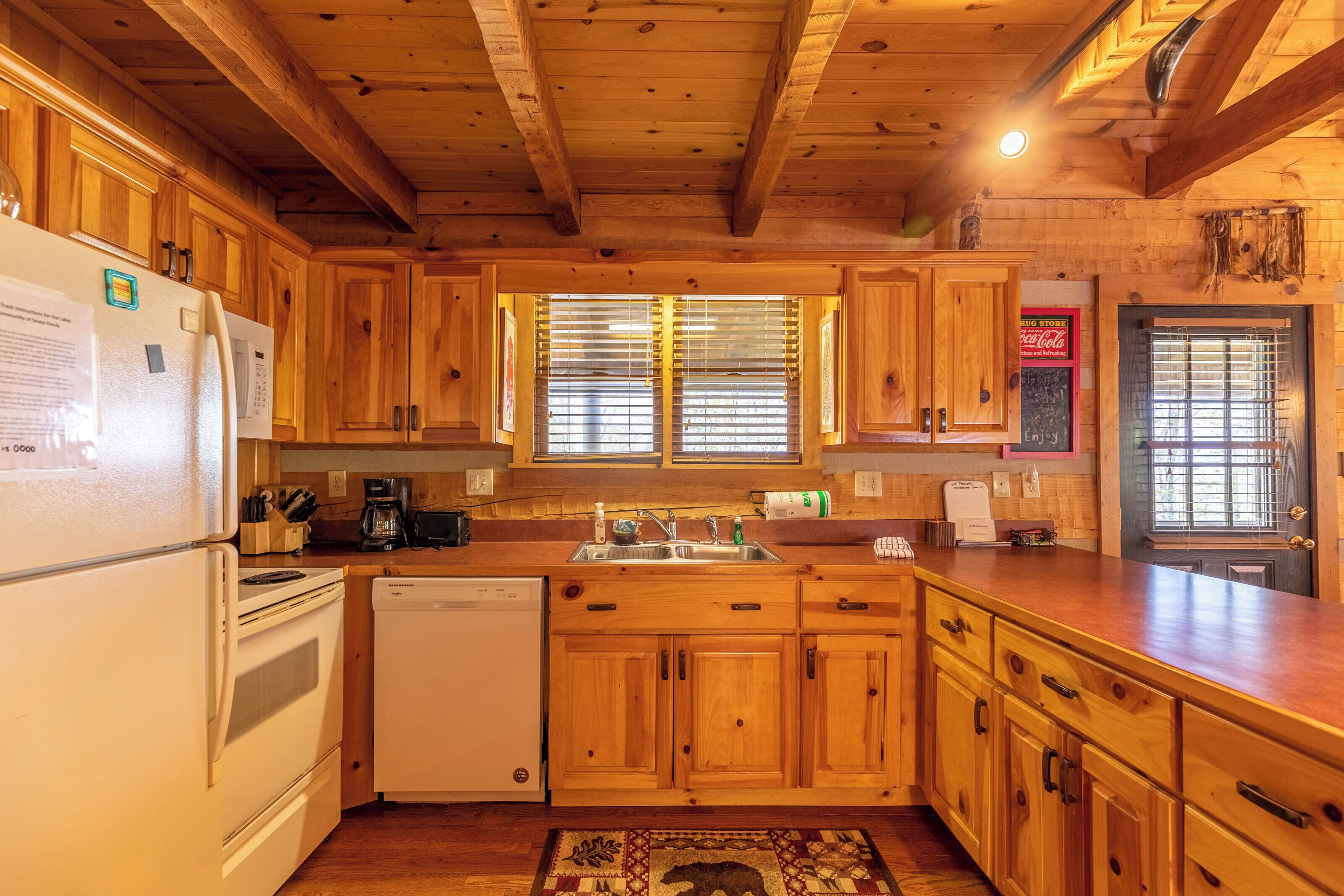 A wooden kitchen with a refrigerator, dishwasher, and wooden cabinets.