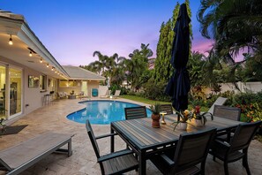 A poolside area with a pool, outdoor furniture, and a view of the house.