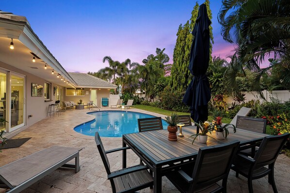 A poolside area with a pool, outdoor furniture, and a view of the house.