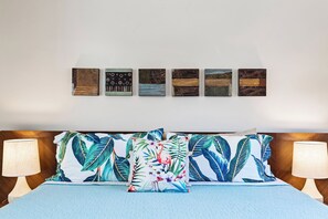 A bed with floral-patterned pillows, a blue blanket, and a headboard with a wooden finish.
