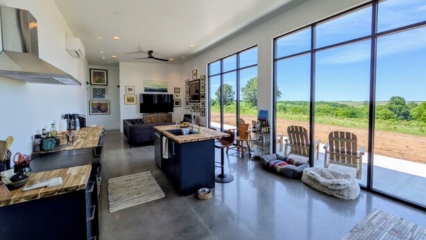 Una cocina amplia con una isla grande, una zona de comedor con sillas y vistas al exterior.