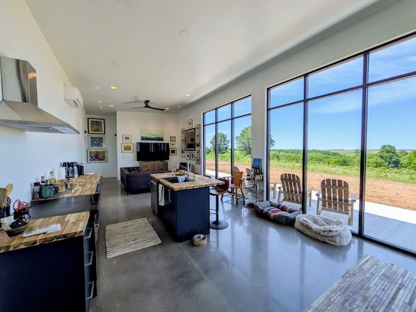 A spacious kitchen with a large island, a dining area with chairs, and a view of the outdoors.