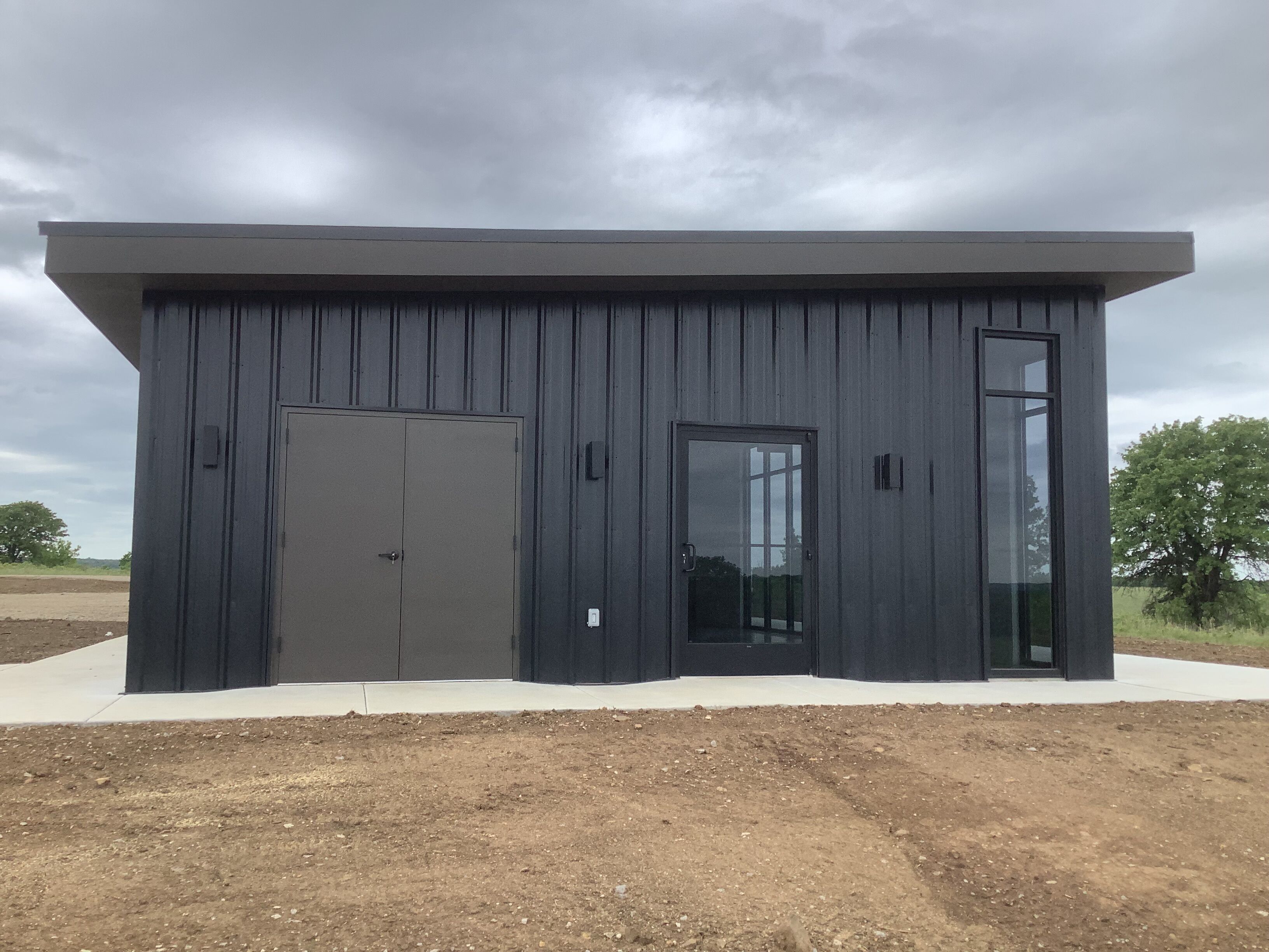 A modern building with a flat roof, a large door, and a window.