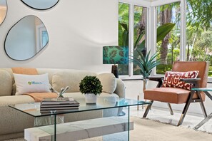 Ein modernes Wohnzimmer mit Glastisch, beiger Couch und braunem Sessel.