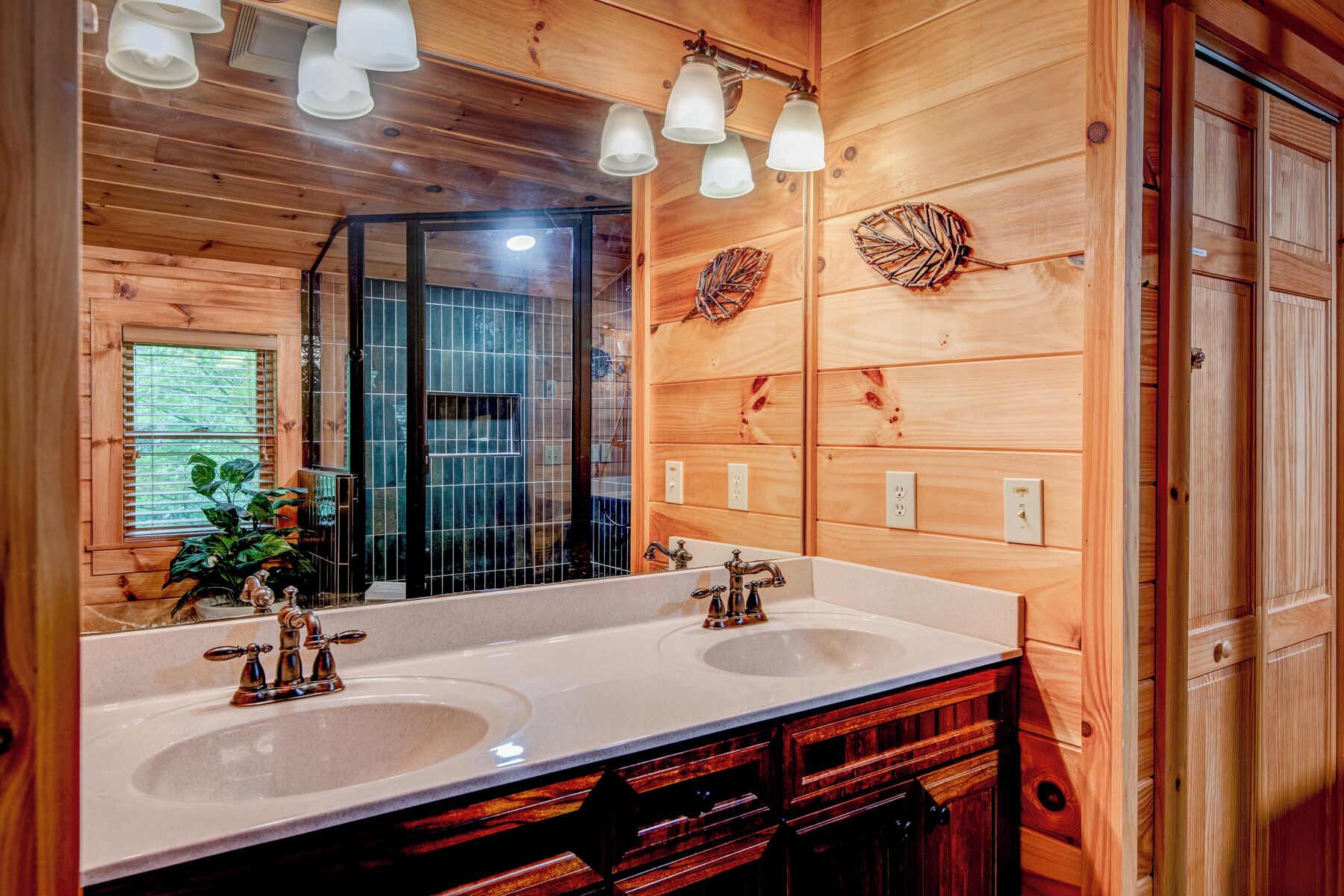 A wooden bathroom with two sinks, a large mirror, and a shower area.