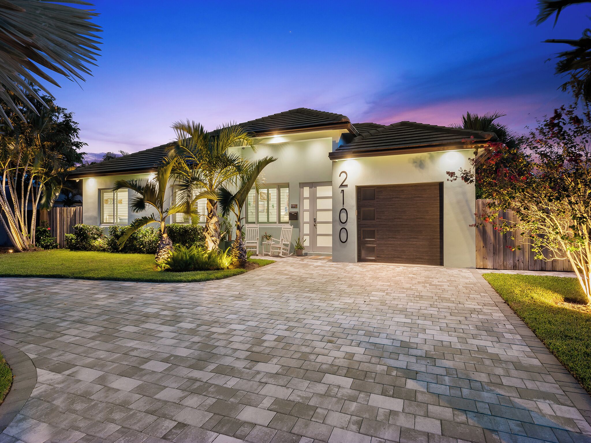 A modern two-story house with a paved driveway, a garage, and a well-maintained lawn.