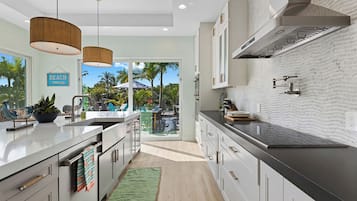 Cozinha moderna com uma ilha grande, eletrodomésticos de aço inoxidåvel e vista para uma årea tropical externa.