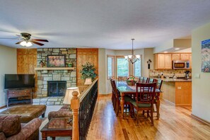 A spacious living area with a stone fireplace, wooden dining table, and a TV on a stand. - Chetola Berkshires 3 - 3BR With 2 Sleeper Sofas-walk To Blowing Rock (Blowing Rock)