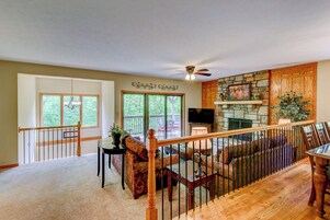 A spacious living room with a fireplace, a balcony with a railing, and a television.