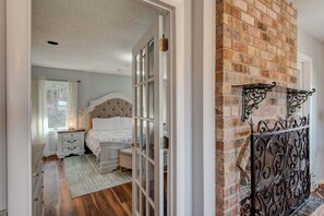A bedroom with a bed, nightstands, a dresser, a window, and a brick wall. - Hilltop Hideaway (Boone)