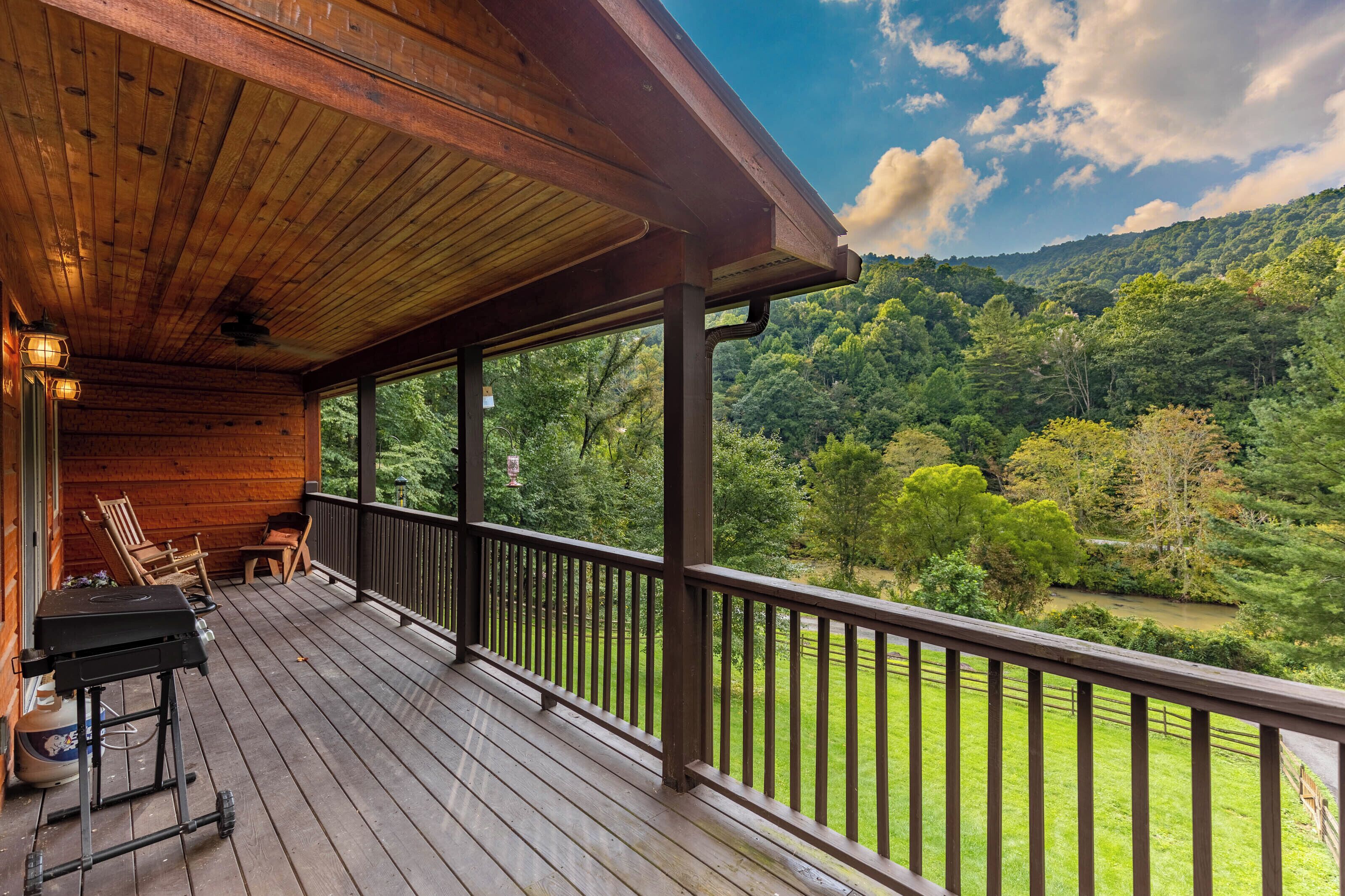 A wooden deck with a view of a forested hillside.