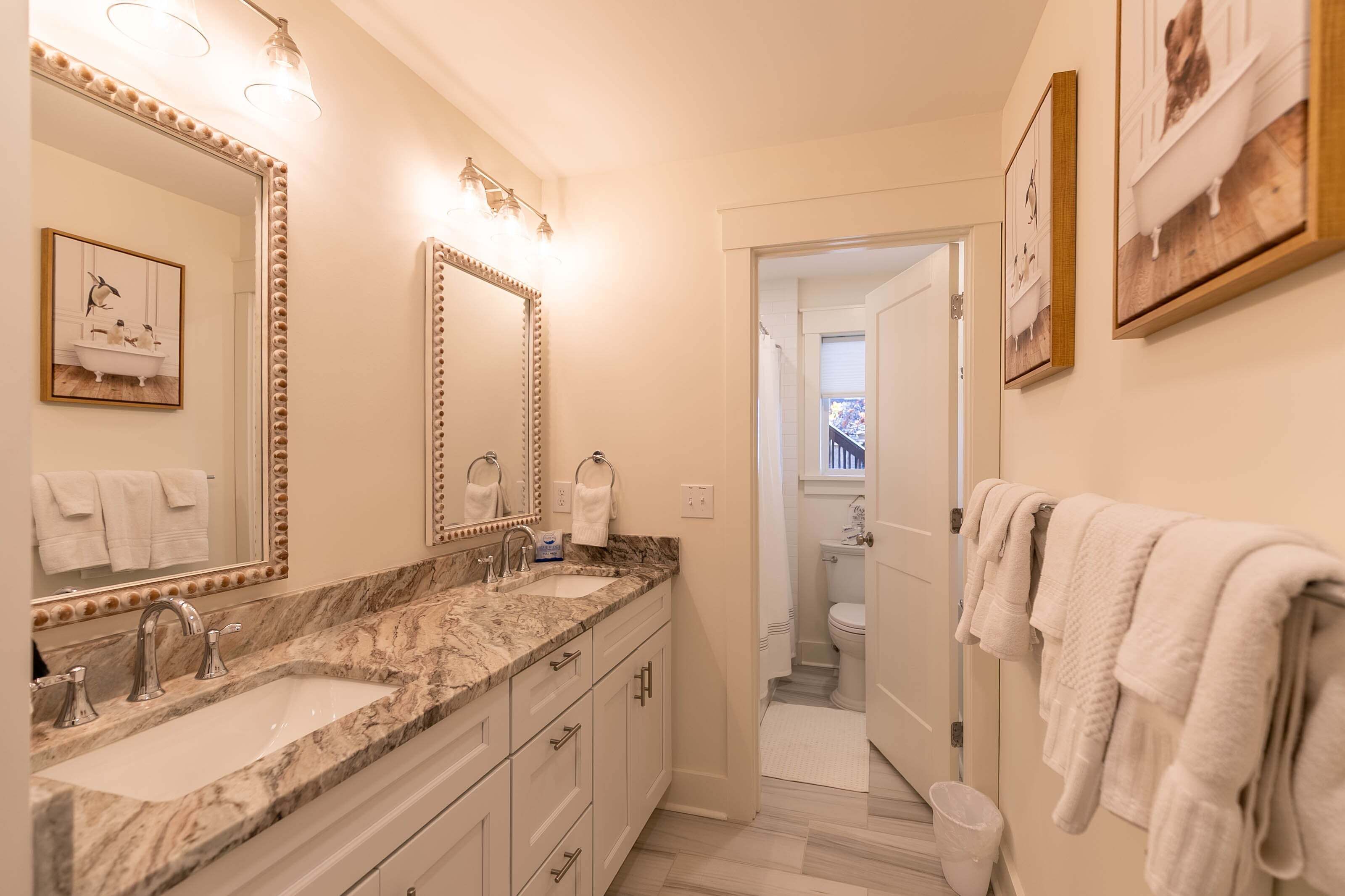 A bathroom with two sinks, a large mirror, and a toilet.