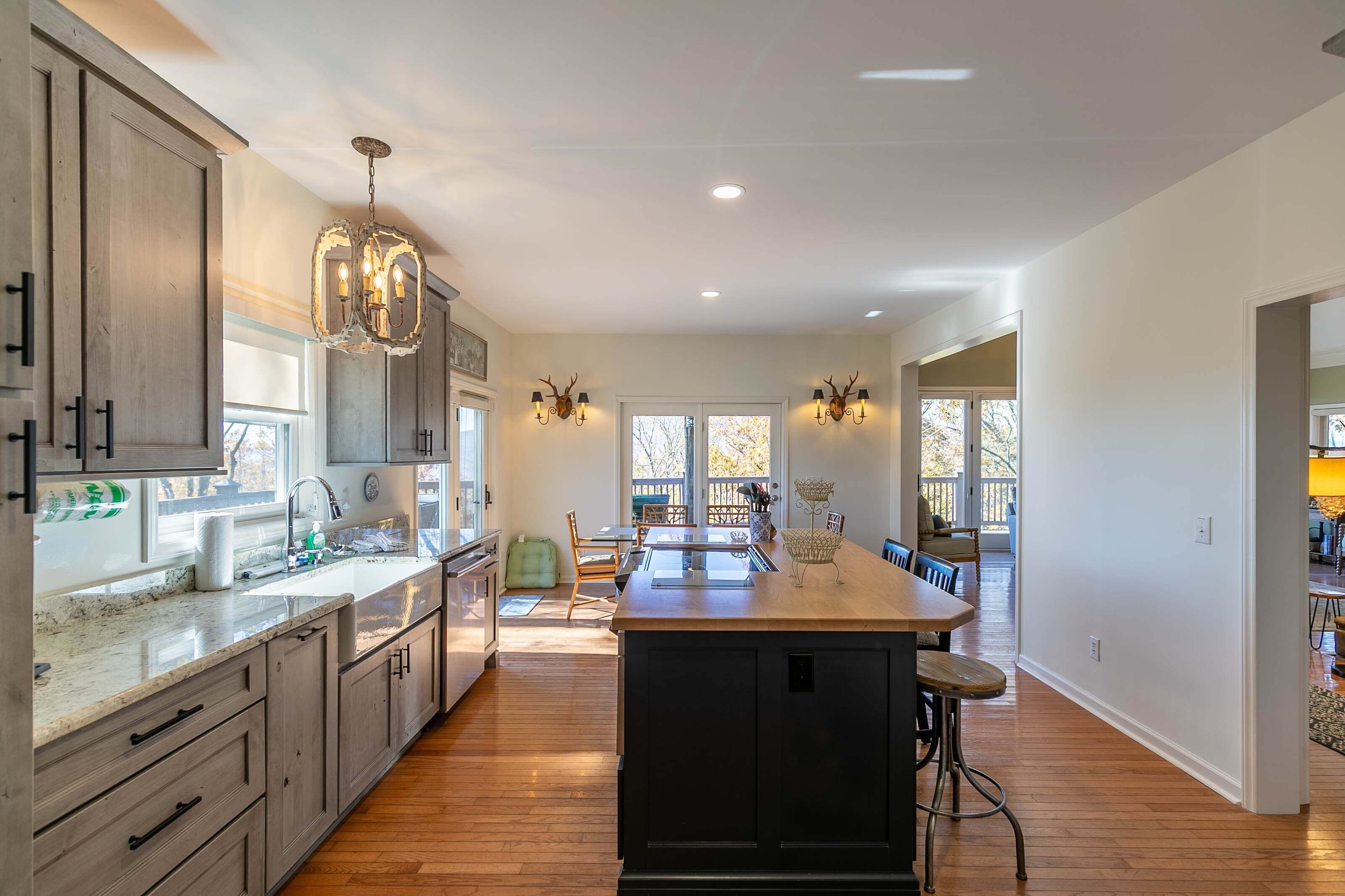 A spacious kitchen with wooden cabinets, a central island, pendant lights, and a dining area with chairs.