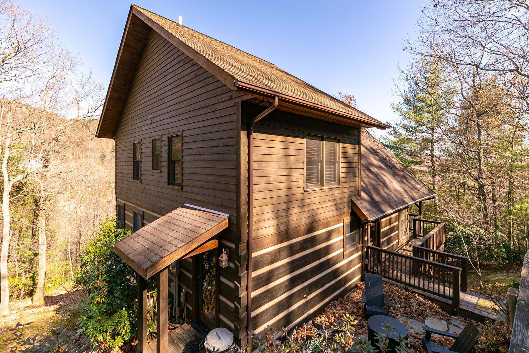 Een houten hut met een veranda, een klein terras en een trap naar een terras.