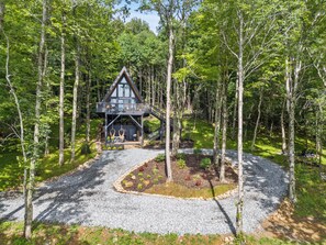 Eine Hütte mit Balkon, umgeben von Bäumen und einem Schotterweg.