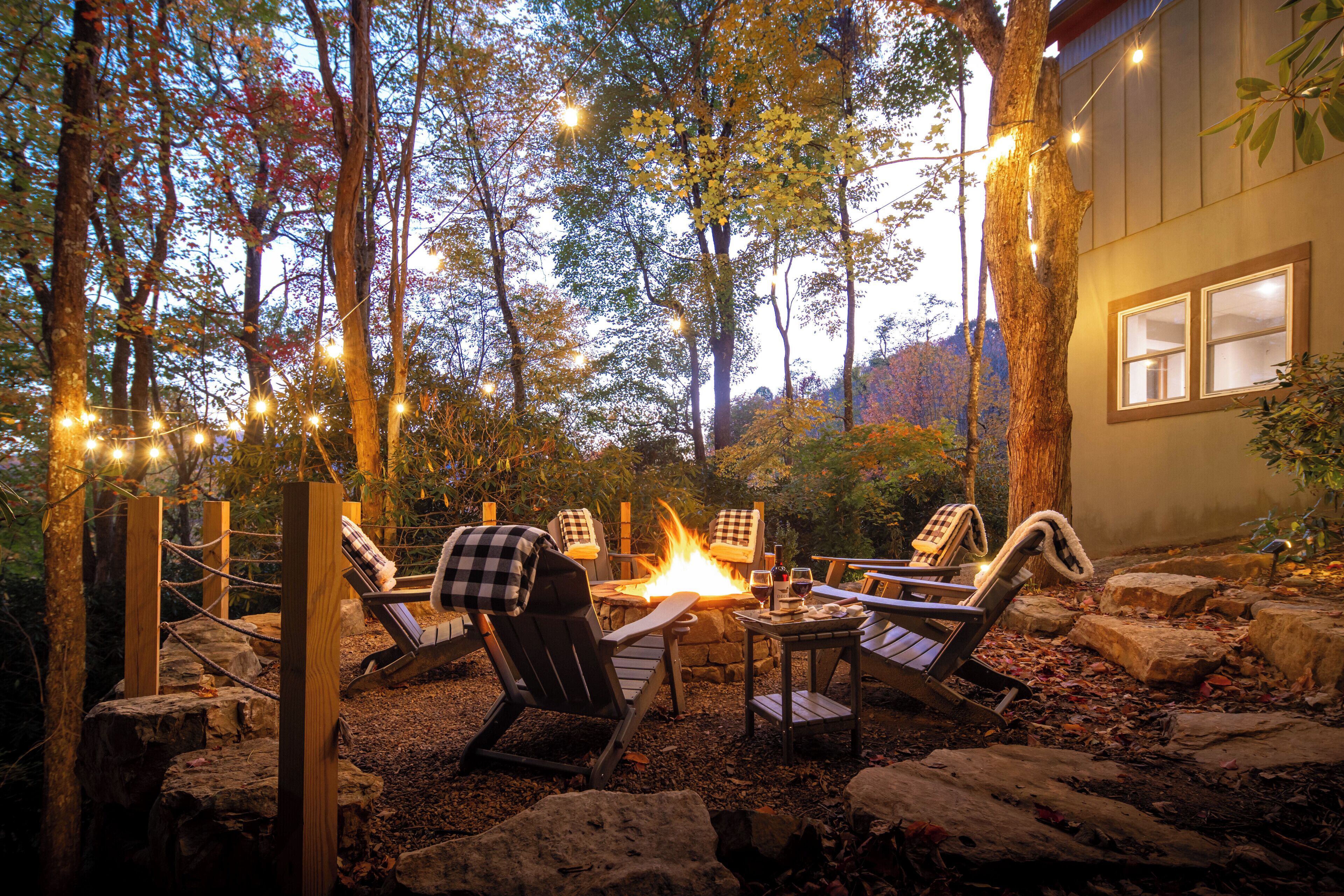 An outdoor seating area with chairs and a fire pit, surrounded by trees and rocks.