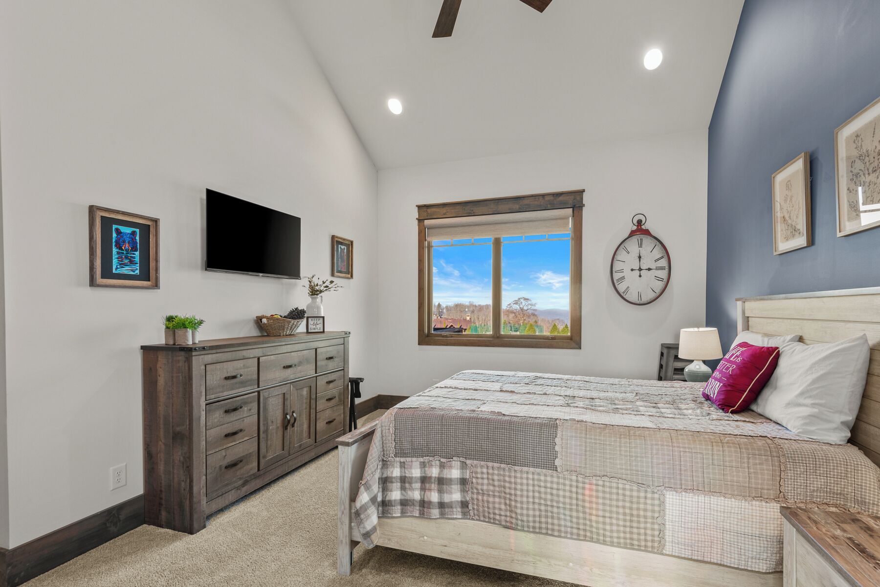 Un dormitorio con cama, cómoda, televisor, ventana y un reloj en la pared.
