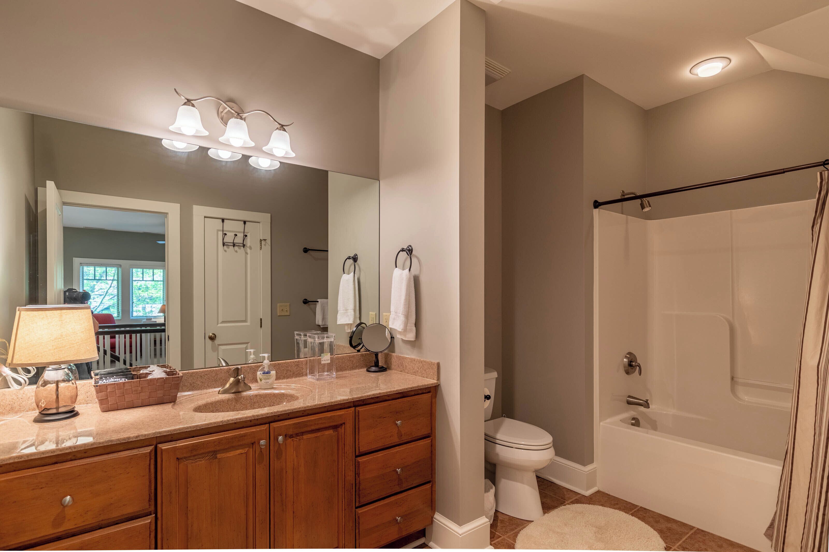 A bathroom with a vanity, sink, mirror, towel rack, toilet, and bathtub.