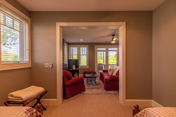 A room with a large window, a ceiling fan, and a red sofa.