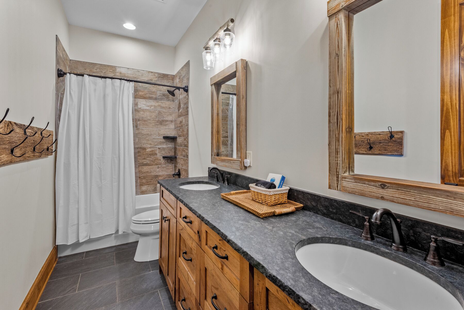 A bathroom with two sinks, a shower, and a toilet.