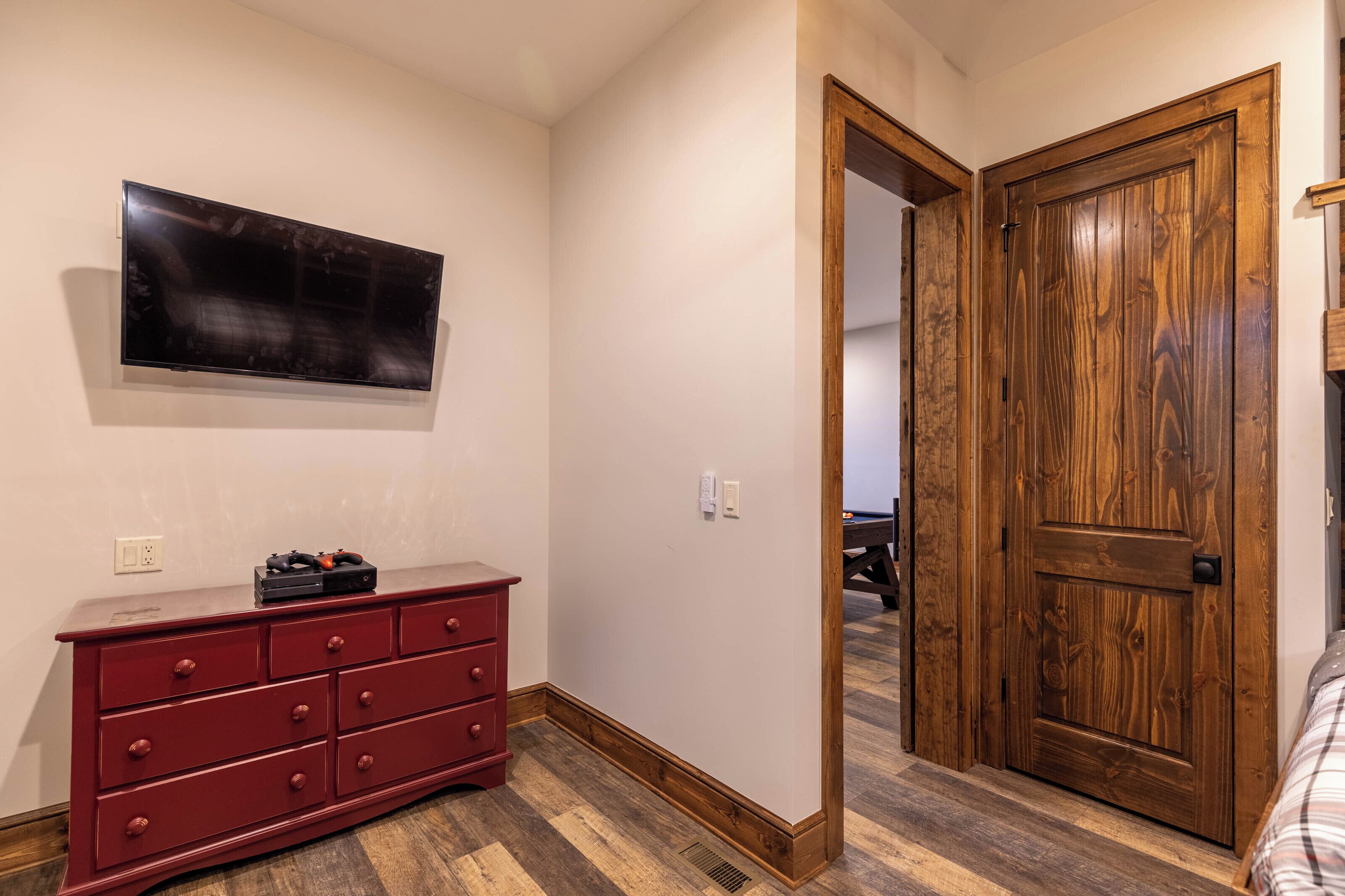 Ein Zimmer mit Holztür, einem roten Schminktisch und einem an der Wand befestigten Fernseher.