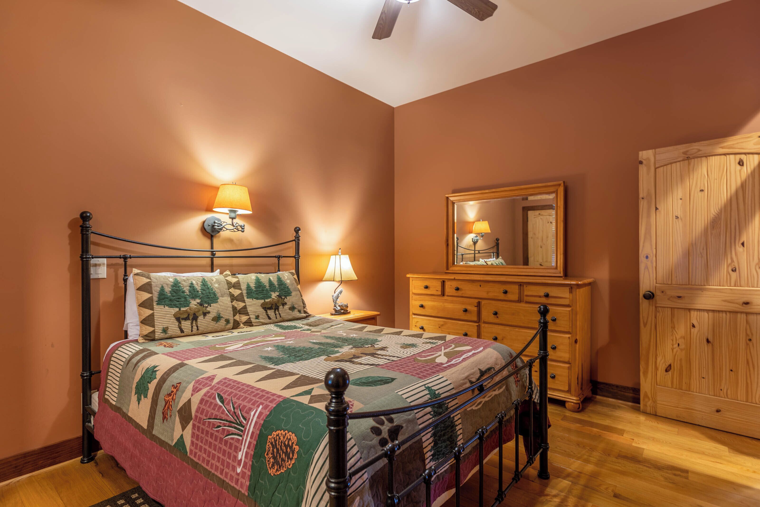 A bedroom with a bed, bedside lamps, a dresser, a mirror, and a wooden door.
