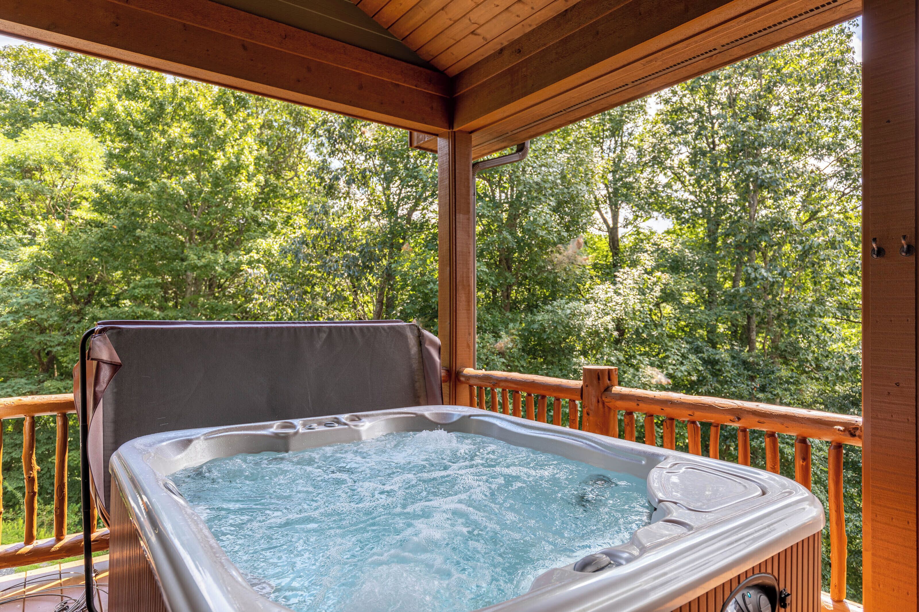 Un bain à remous sur une terrasse en bois, avec vue sur une forêt.