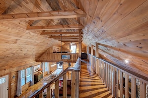 Un interior de madera con una escalera que conduce a una zona tipo altillo, que incluye una mesa de comedor y sillas.