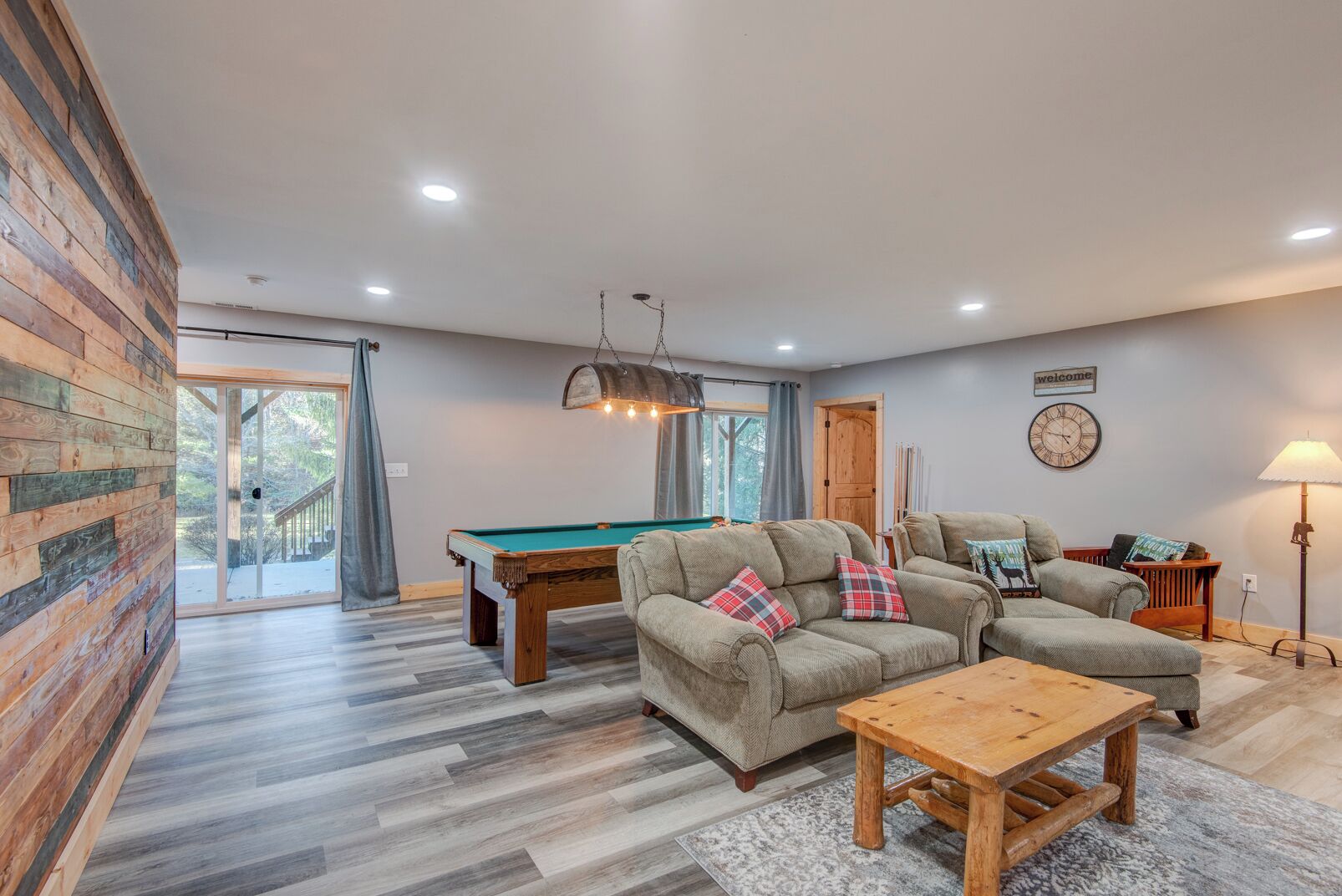 A cozy living room with a pool table, two sofas, a coffee table, and a lamp.