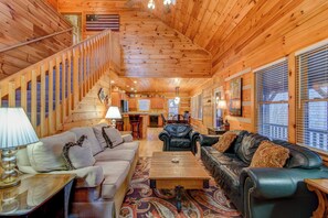 A log cabin interior with a living room, kitchen, and staircase. - 1 Abundant Life (Vilas)