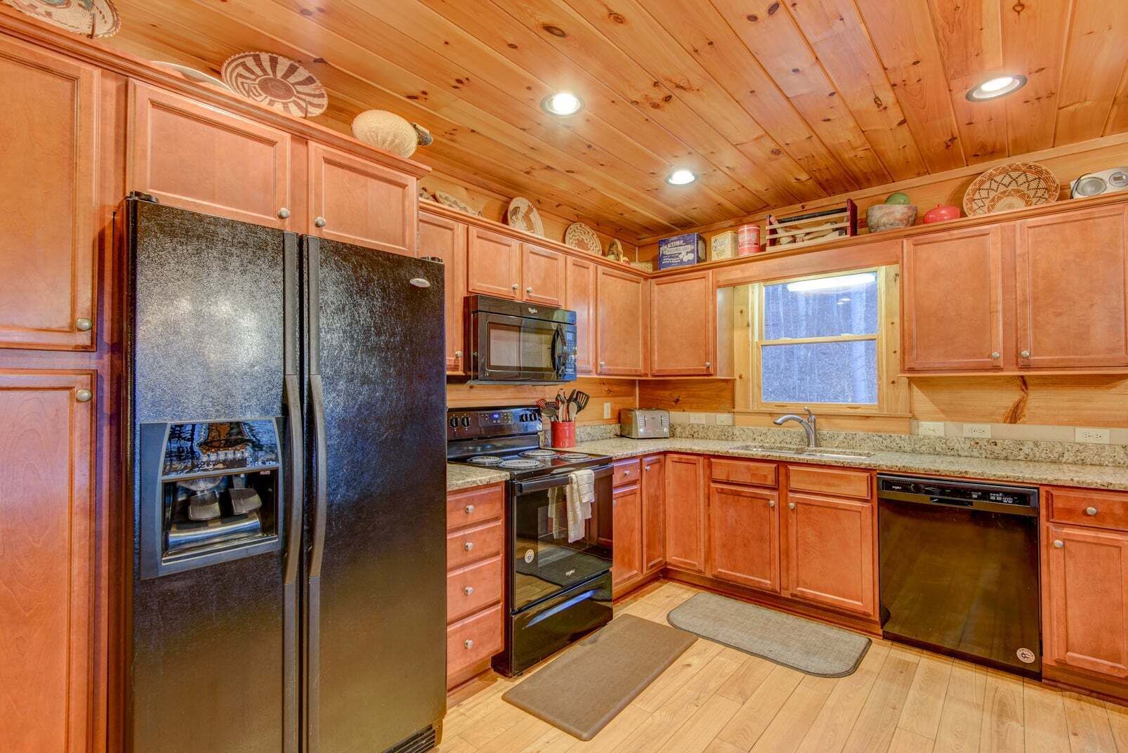 A kitchen with wooden cabinets, a refrigerator, stove, microwave, and dishwasher.