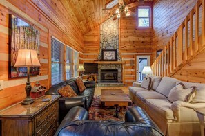 A log cabin interior with a fireplace, leather sofas, and a stone accent wall. - 1 Abundant Life (Vilas)