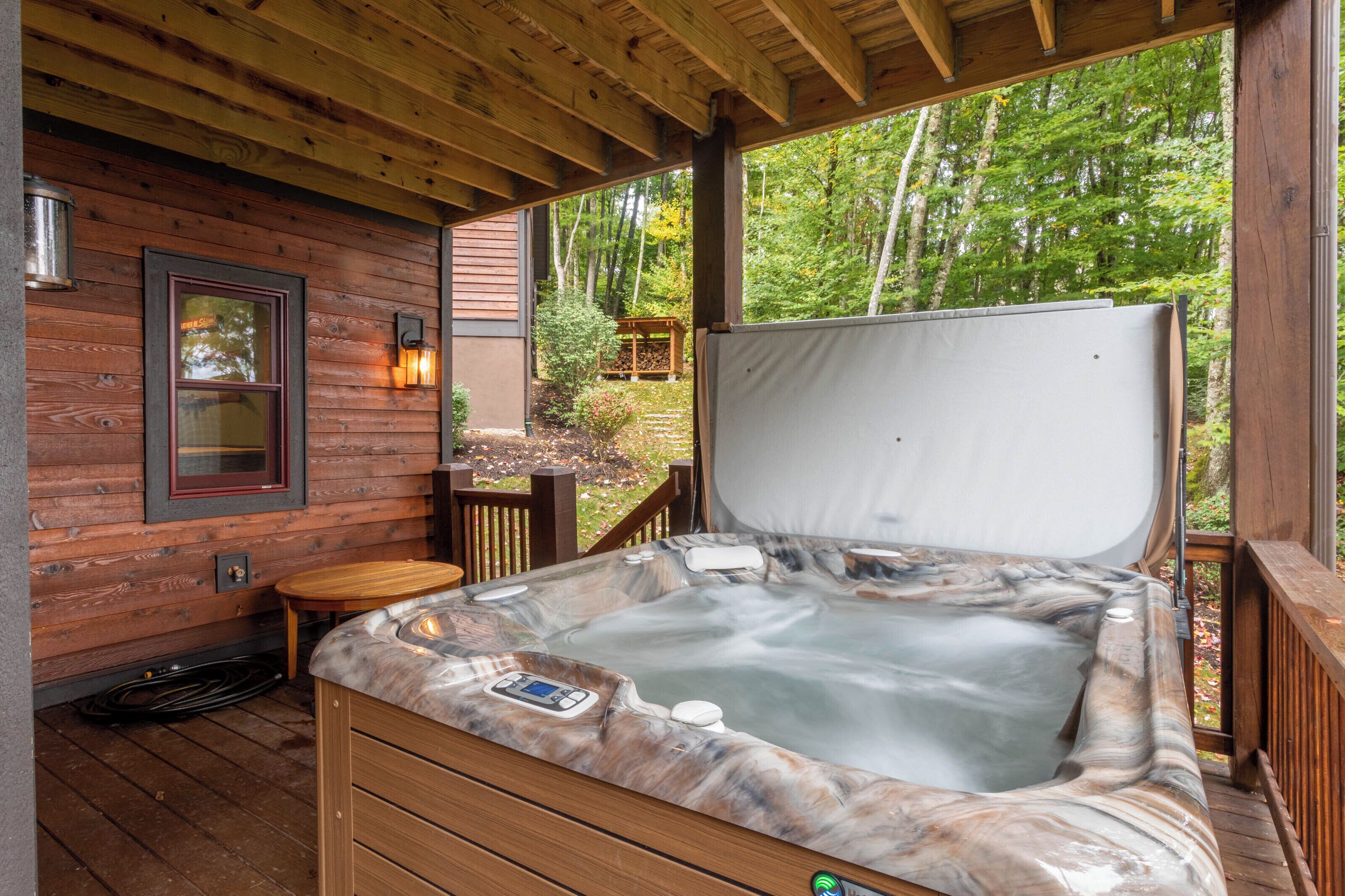 A hot tub with a wooden deck, a wooden cabin with a window, and a wooden fence.
