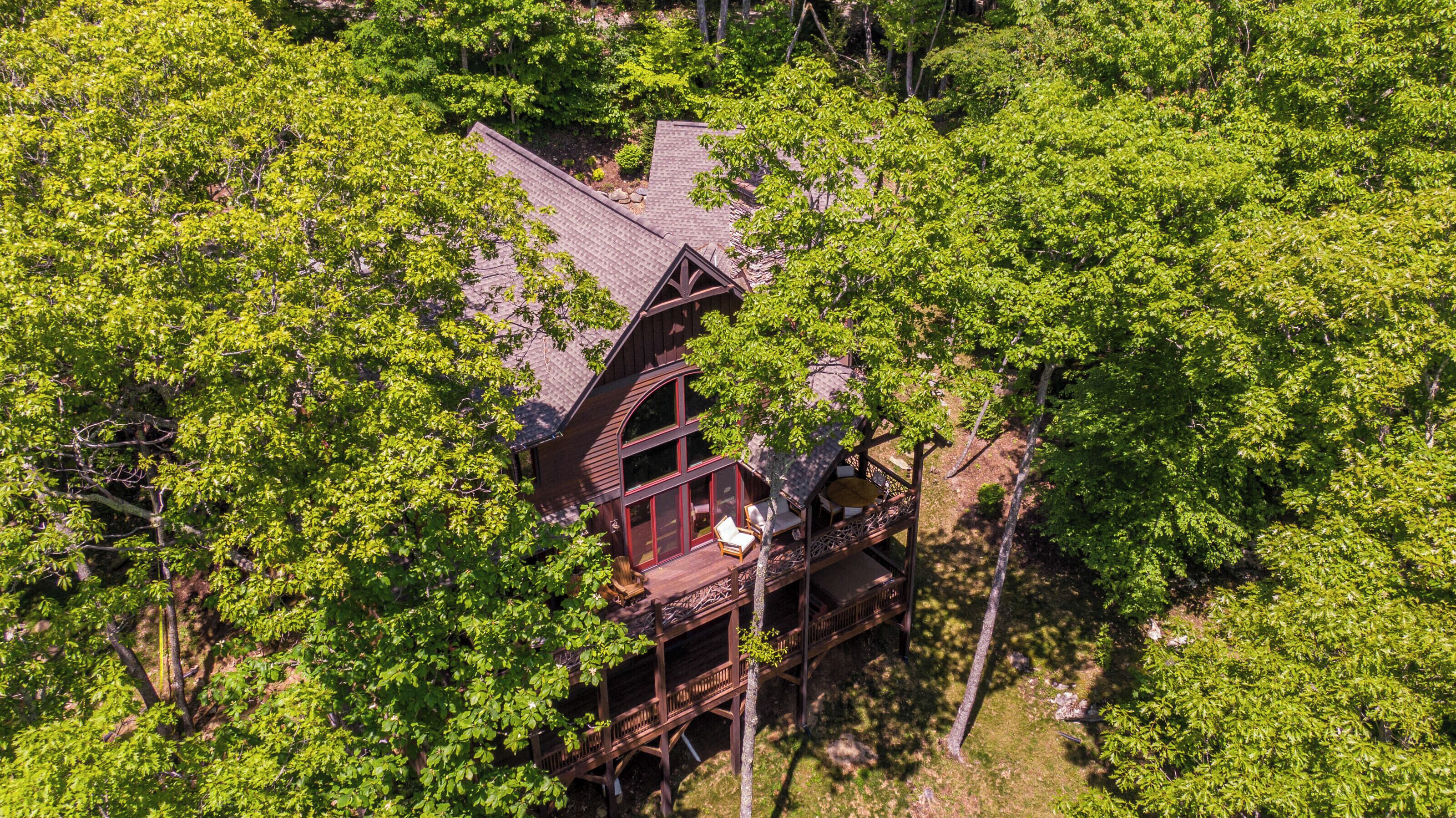 A wooden cabin surrounded by dense green trees.