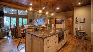 A spacious kitchen with wooden cabinets, a granite countertop, and pendant lighting. - Eagles Landing at Eagles Nest (Banner Elk)
