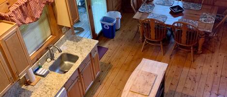 A cabin interior with a kitchen area, dining table, and chairs.