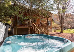 A wooden cabin with a hot tub and a staircase leading to a deck. - Baird's Creek Cabin (Vilas)