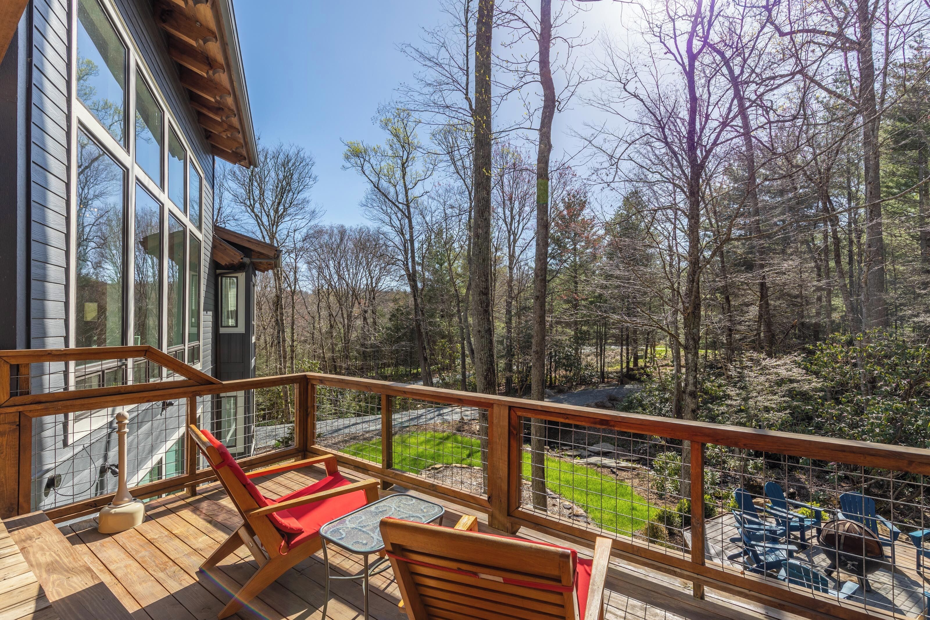 A wooden deck with outdoor furniture, overlooking a forested area.