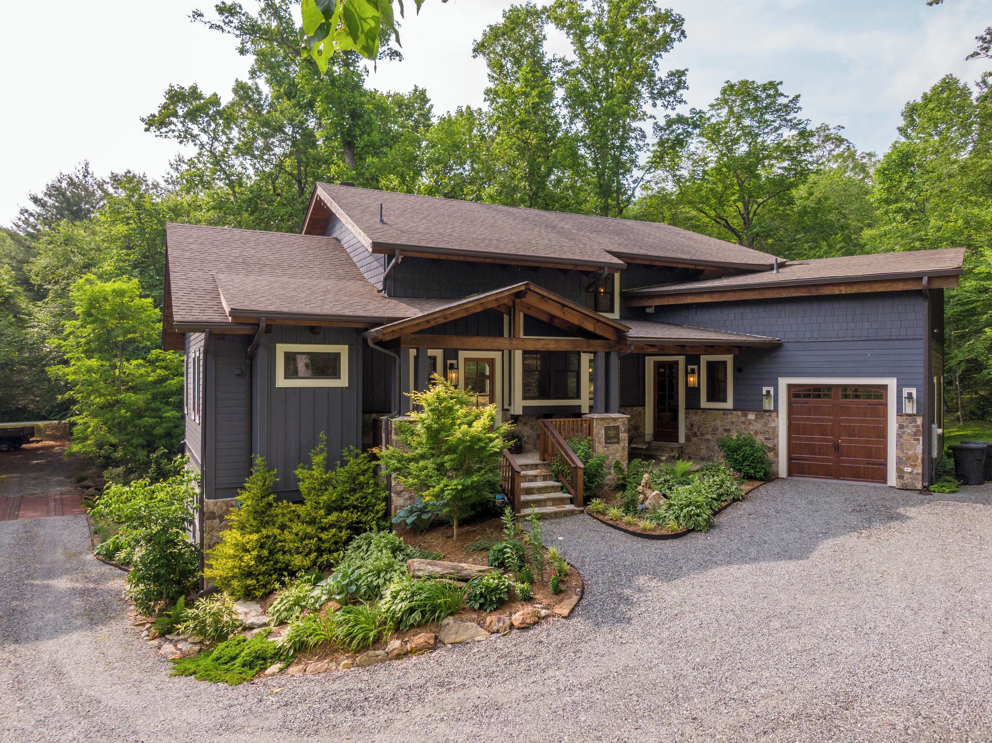 A two-story house with a stone foundation, a front porch, and a garage.