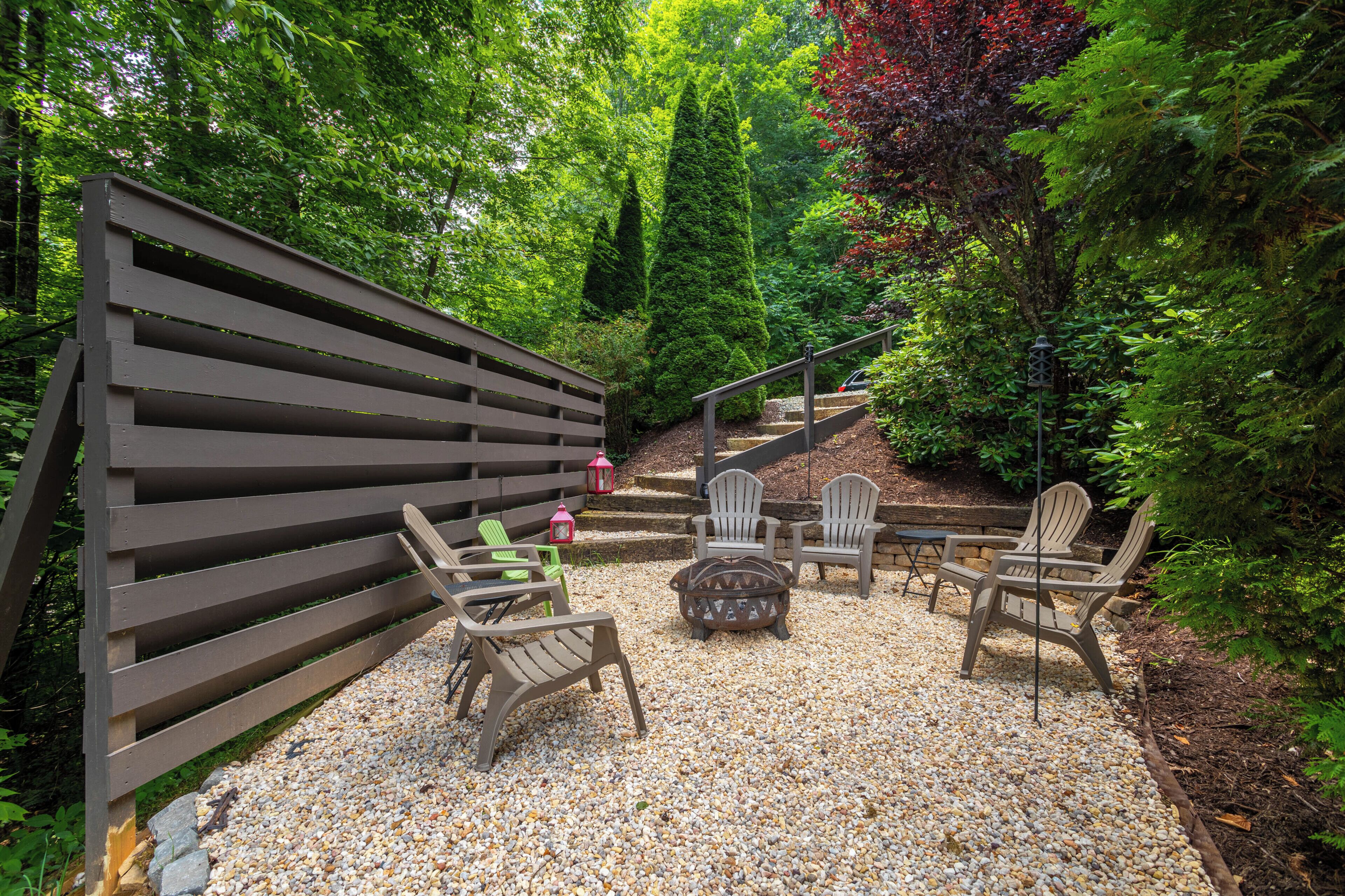 A patio area with a wooden fence, outdoor seating with chairs and a table, and a gravel ground.