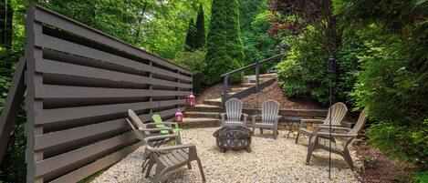 A patio area with a wooden fence, outdoor seating with chairs and a table, and a gravel ground.