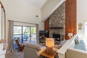 A living room with a stone fireplace, a television, and a sofa.