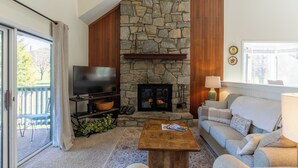 A living room with a stone fireplace, a television, a sofa, and a coffee table.
