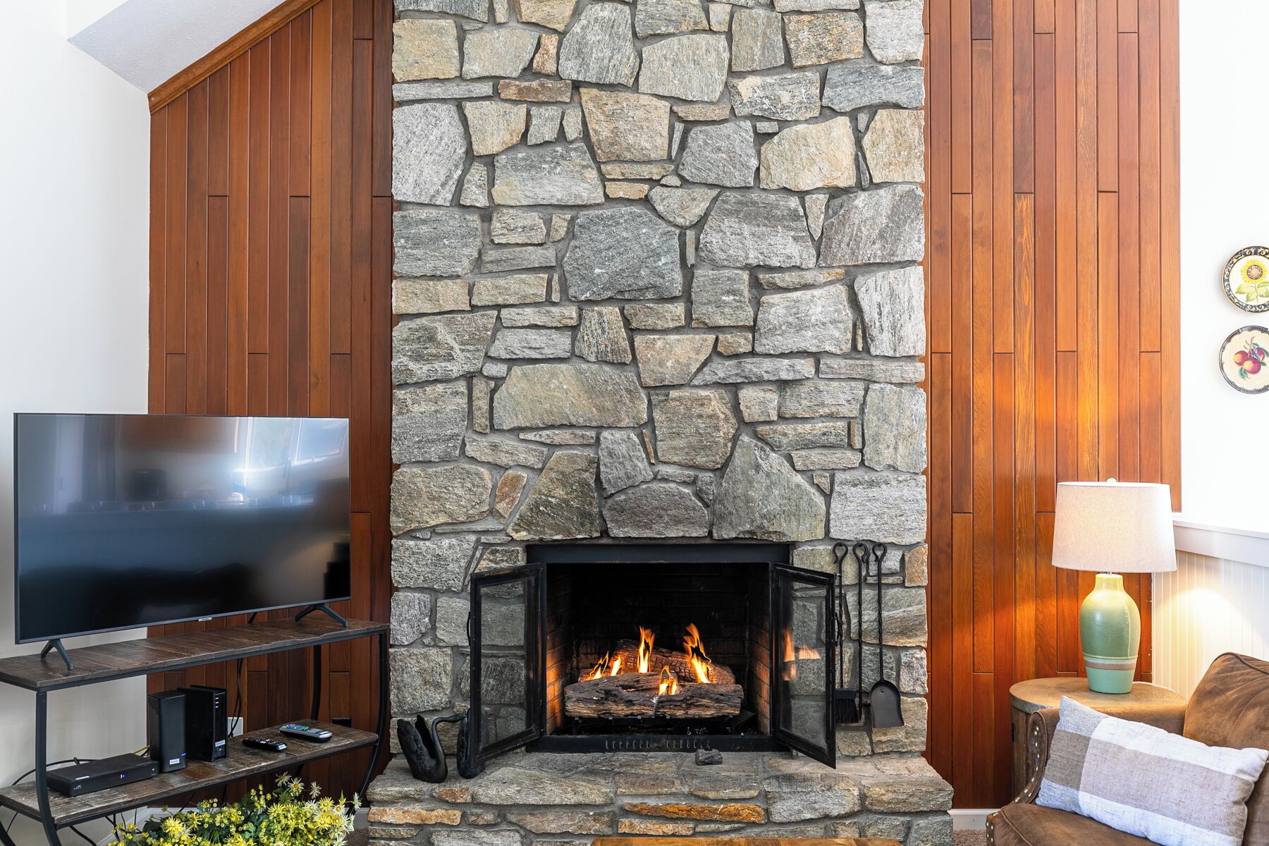 A stone fireplace with a TV on a wooden stand to the left.