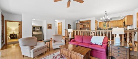 A living room with a ceiling fan, a red sofa, a wooden coffee table, and a patterned rug.