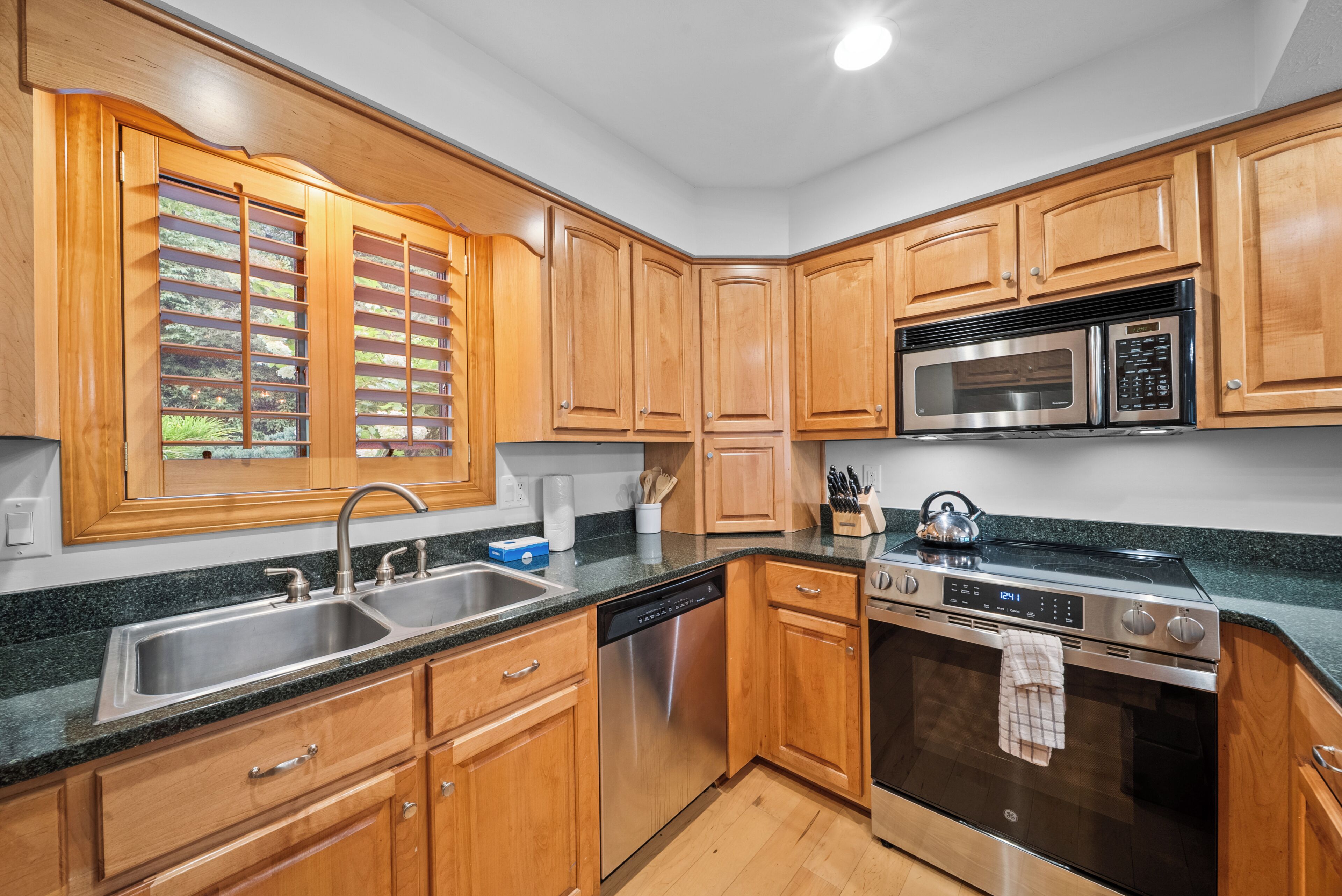 A kitchen with wooden cabinets, stainless steel appliances, a dishwasher, and a microwave.