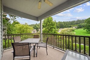 A covered outdoor area with a table and chairs, a view of a lake, and surrounding greenery. - Chetola Sierra 1 (Blowing Rock)